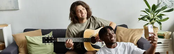 A happy couple enjoys strumming a guitar and taking selfies in their cozy living room. — Stock Photo