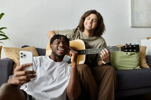 Zwei Partner genießen einen gemütlichen Moment zu Hause, spielen Gitarre und teilen Lächeln und Liebe. — Stockfoto