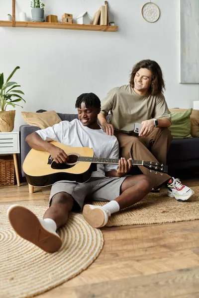 Dois homens compartilham um momento amoroso enquanto tocam guitarra e relaxam em casa. — Fotografia de Stock