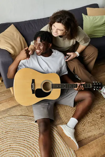 A couple enjoys making music in their cozy living room, sharing laughter and love together. — Stock Photo