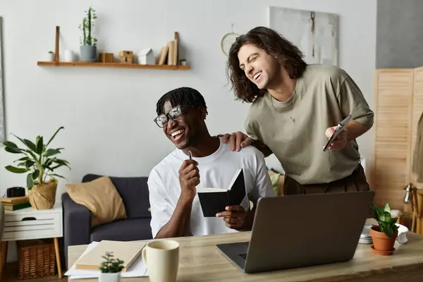A happy gay couple engages in a creative project at home, sharing laughter and ideas. — Stock Photo