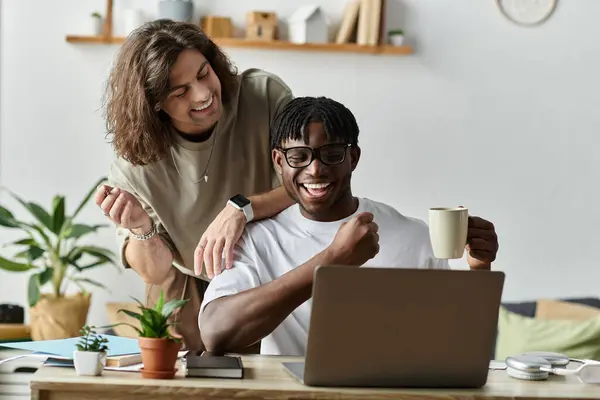 A happy couple engages with each other while sharing smiles and laughter over a laptop. — Stock Photo