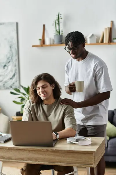A joyful couple shares moments at home while one partner works on the laptop. — Stock Photo