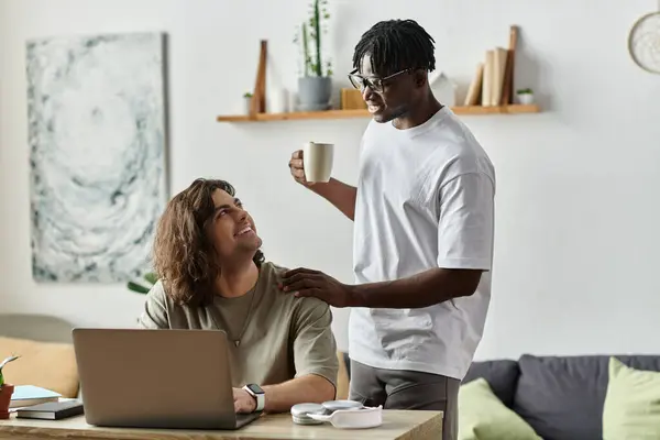 Two partners share a tender moment at home, engaging in work and sipping coffee joyfully. — Stock Photo