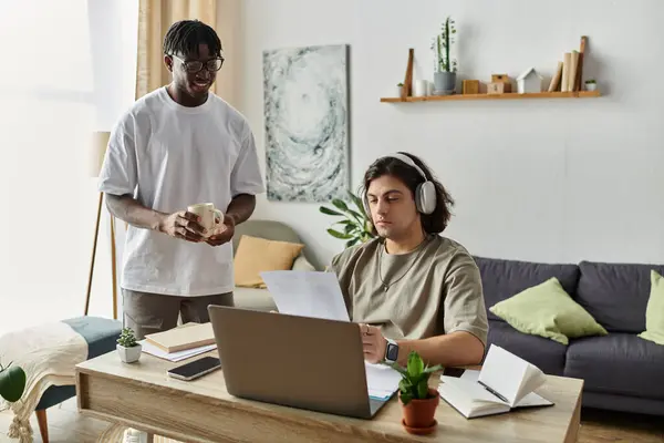 A happy couple shares a tender moment while juggling work and coffee at home. — Stock Photo