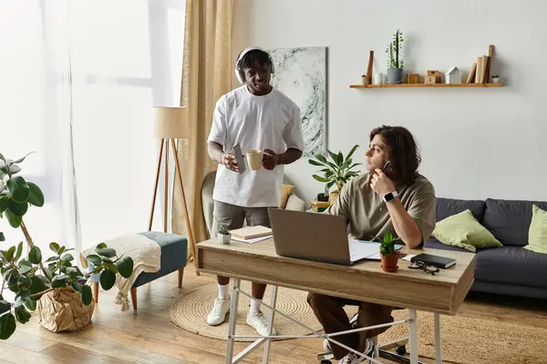 Two partners share a warm moment at home, one working diligently while the other offers support. — Stock Photo