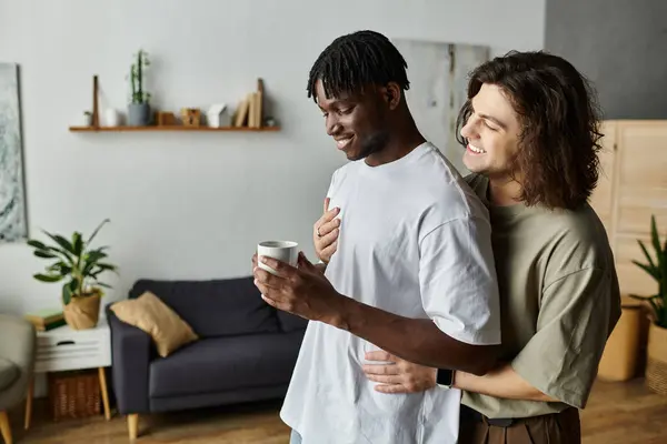 Dois parceiros abraçam-se amorosamente em casa, desfrutando de um momento tranquilo e íntimo, juntamente com uma xícara. — Fotografia de Stock