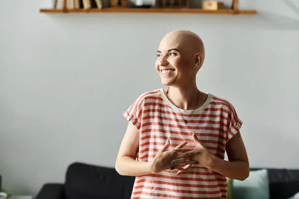 A bald young woman radiates happiness while standing in her inviting home space. — Stock Photo