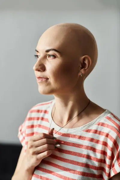 A young bald woman stands thoughtfully, showcasing her beauty and strength against gentle light. — Stock Photo
