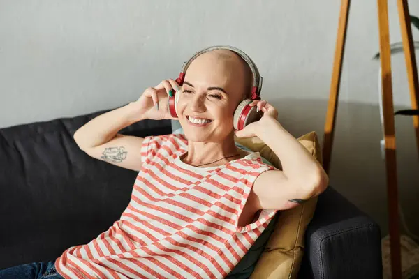 The young woman, embracing her baldness, radiates happiness while listening to music. — Stock Photo