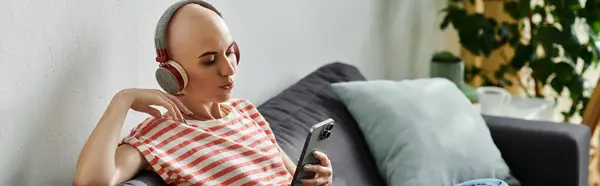 Лисий жінка взаємодіє зі своїм смартфоном, слухаючи музику в комфортній обстановці. — стокове фото