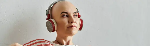 A beautiful bald woman enjoys music with headphones, embracing her unique beauty and style. — Stock Photo