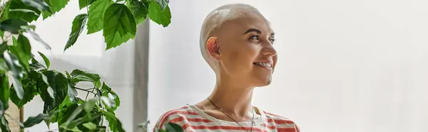 A young bald woman embraces her beauty while enjoying a serene moment indoors with greenery. — Stock Photo