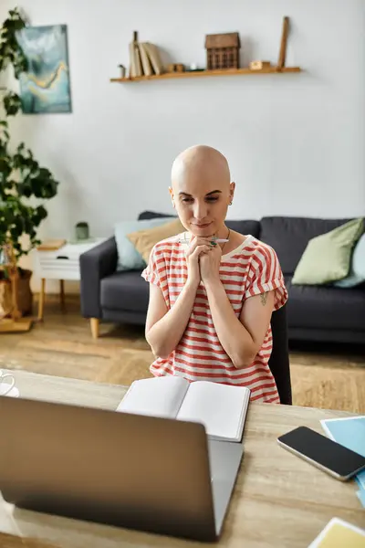 Eine junge Frau mit Glatze und Haarausfall betrachtet ihre Arbeit in einem einladenden Wohnraum. — Stockfoto