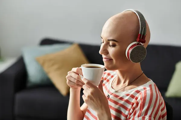 A young beautiful bald woman with alopecia savors a cup of coffee while relaxing at home. — Stock Photo