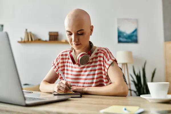 A young bald woman focuses on her notes while surrounded by a bright, inviting interior. — Stock Photo