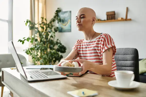 A beautiful bald woman savors a peaceful morning, enjoying breakfast while working on her laptop. — Stock Photo