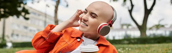 A joyful bald woman relaxes in a sunny park, enjoying her favorite tunes through headphones. — Stock Photo