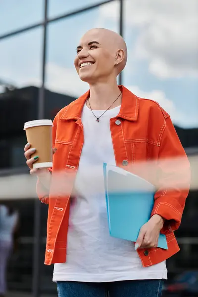 A cheerful bald woman stands outdoors, savoring her coffee while holding colorful notes. — Stock Photo