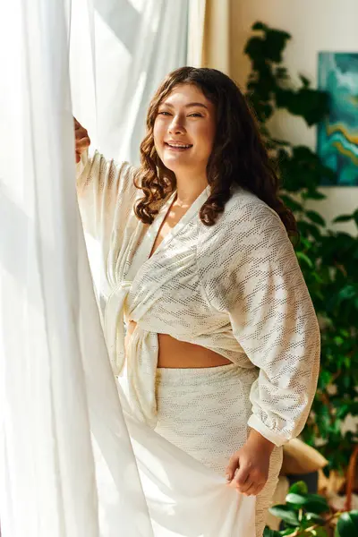 A joyful plus size woman basks in sunlight streaming through her window, radiating positivity. — Stock Photo
