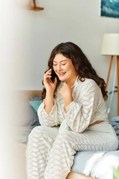 A young plus size woman enjoys a lively phone conversation, smiling and relaxed at home. — Stock Photo