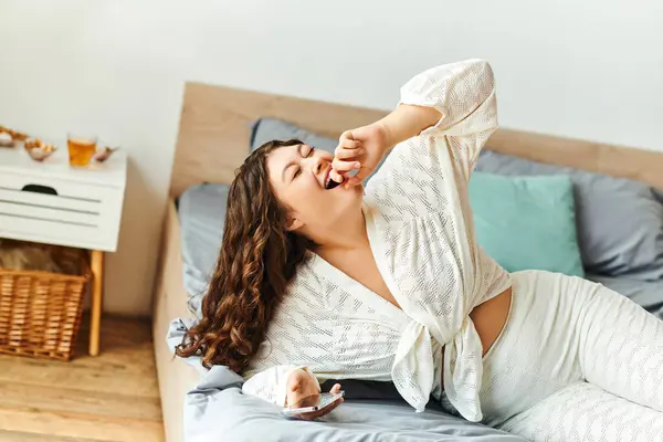 Веселая женщина plus size сидит в своей уютной спальне, радуясь мирному утру. — стоковое фото