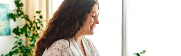 A young plus size woman smiles softly as she embraces comfort in her bright, cozy living space. — Stock Photo
