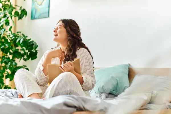 A young woman cozies up in her comfortable bedroom, lost in a good book. — Stock Photo