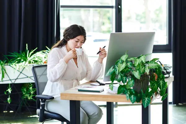 In uno spazio luminoso e confortevole, una giovane donna sorseggia caffè e si concentra sul suo lavoro in ufficio.. — Foto stock