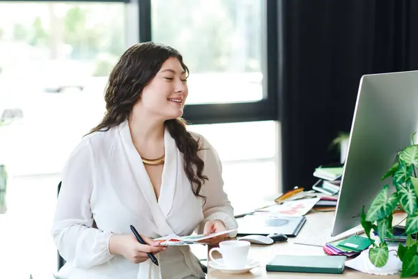 The woman sits comfortably at her desk, immersed in her creative work with a smile. — Stock Photo