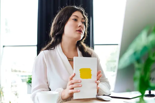A young plus size woman sits peacefully at office, creatively exploring her artistic side. — Stock Photo