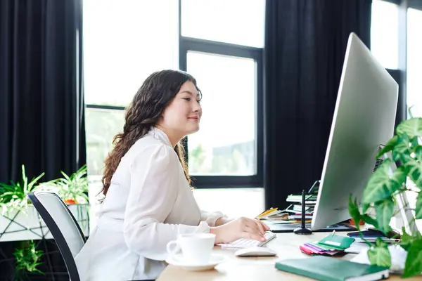 A young plus size woman works at her office, focused and surrounded by plants. — Stock Photo