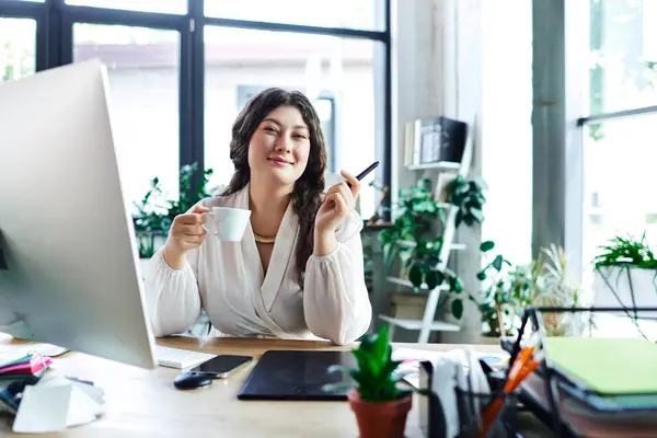 A young woman relaxes at her office with coffee, smiling while working on her tasks. — Stock Photo