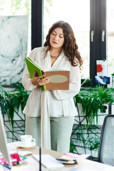 A young plus size woman stands in a bright room, engrossed in reading a book while relaxed. — Stock Photo