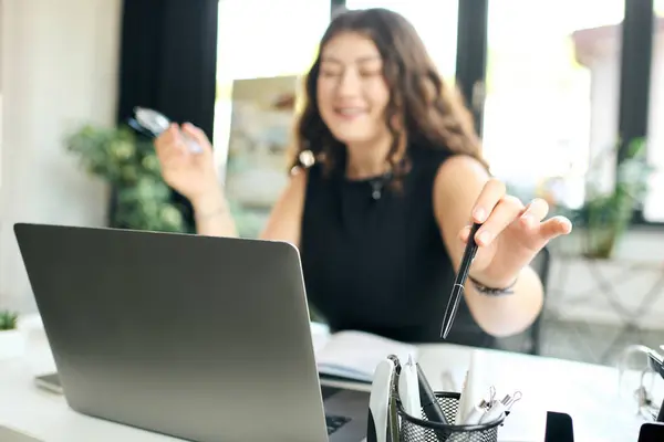 A cheerful young plus size woman with long curly hair interacts with her laptop, immersed in her work while smiling. — Stock Photo