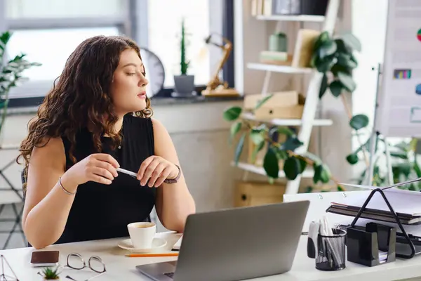 A confident plus size woman sits at her desk, sipping coffee and thoughtfully contemplating her projects in a vibrant office. — Stock Photo