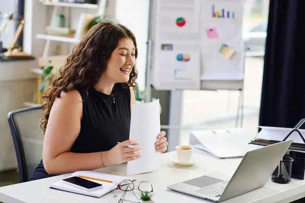 Una giovane e vivace professionista si impegna con il suo lavoro, portando positività in ufficio durante la revisione di documenti importanti. — Foto stock