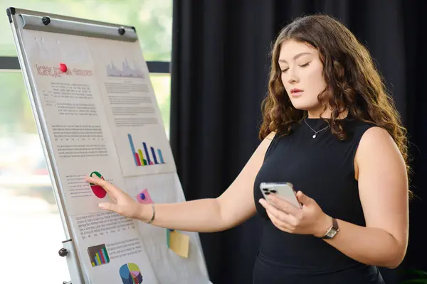 A confident plus-size businesswoman reviews her charts while discussing insights in the trendy office environment. — Stock Photo