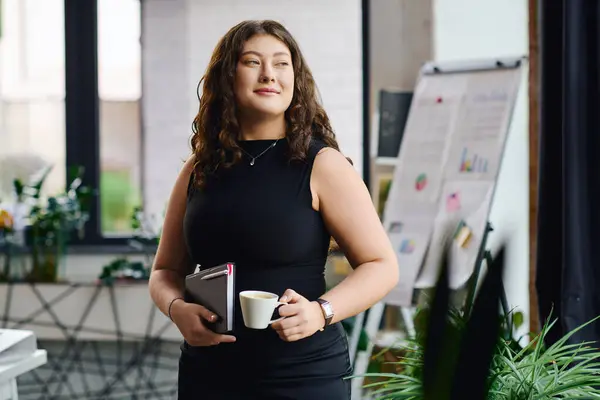 Un abile professionista plus-size con i capelli ricci gode di un momento di calma, tenendo il caffè in uno spazio ufficio vibrante. — Foto stock