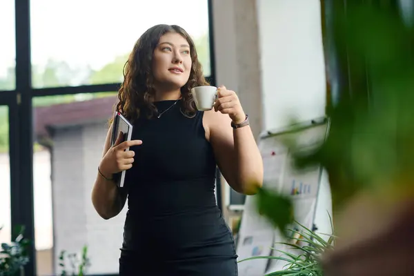 Eine selbstbewusste junge Frau mit lockigem Haar macht eine Kaffeepause und verbindet Professionalität und Stil in einem lebendigen Büroumfeld. — Stockfoto