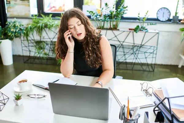 A young plus-size businesswoman multitasks in a lively office, making a call while surrounded by plants and notes. — Stock Photo