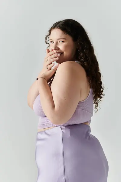 A lovely plus size woman smiles charmingly while adjusting her outfit with grace. — Stock Photo