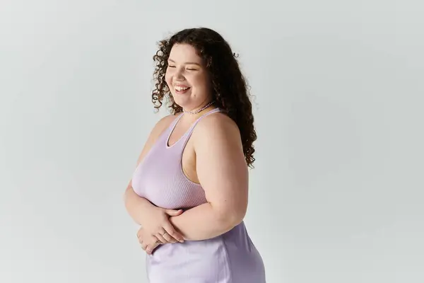 A joyful plus size woman smiles confidently while showcasing her elegance in a pastel dress. — Stock Photo