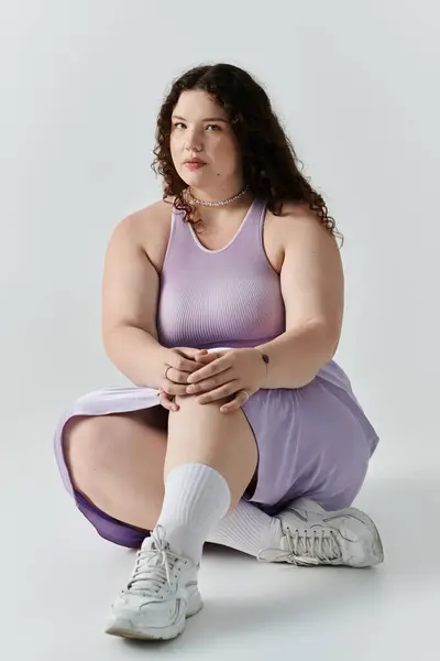 A confident plus size woman sits gracefully, highlighting her beauty and style in pastel colors. — Stock Photo