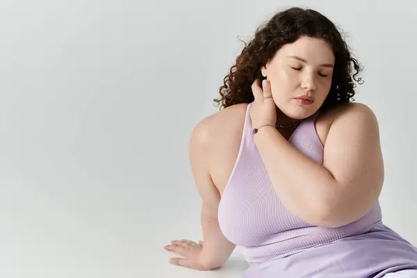 Una hermosa mujer de talla grande posa graciosamente mientras se toca suavemente el cuello, irradiando confianza. - foto de stock