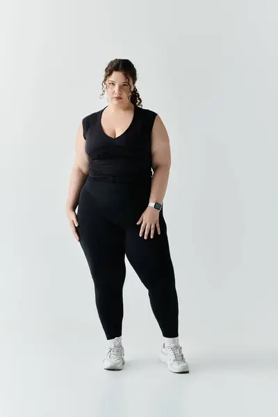 A beautiful plus size woman poses gracefully in fitted black attire, showcasing her elegance. — Stock Photo