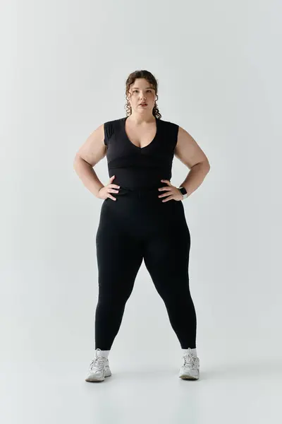 An elegant plus size woman stands confidently in fitted attire, showcasing her beauty and strength. — Stock Photo