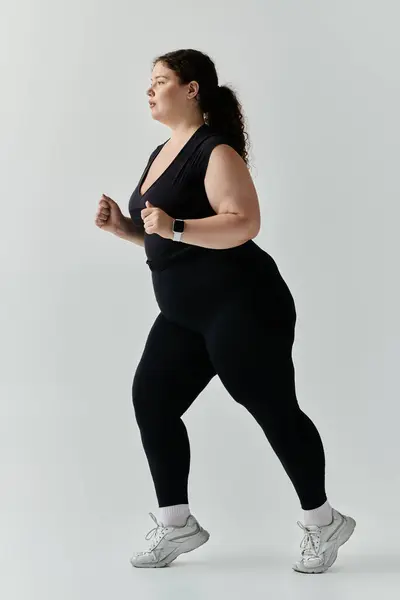 A confident plus size woman jogs with elegance, showcasing her active lifestyle in stylish attire. — Stock Photo