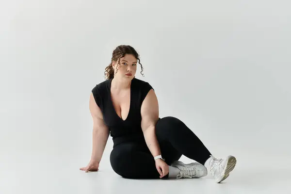 A stylish plus size woman confidently poses against a light backdrop. — Stock Photo