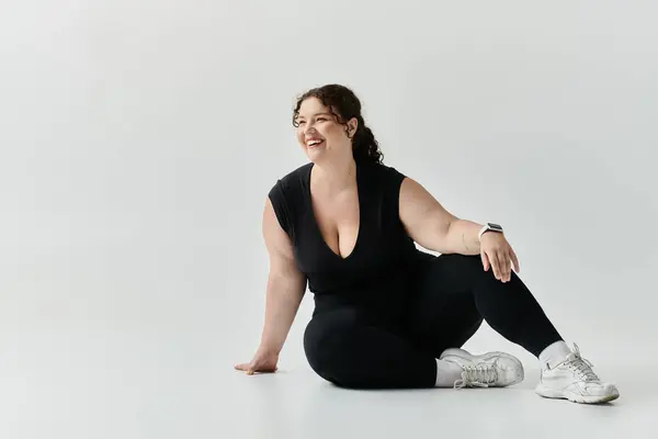 Una donna radiosa plus size siede elegantemente, ridendo e godendo il momento di abbracciare la sua bellezza. — Foto stock